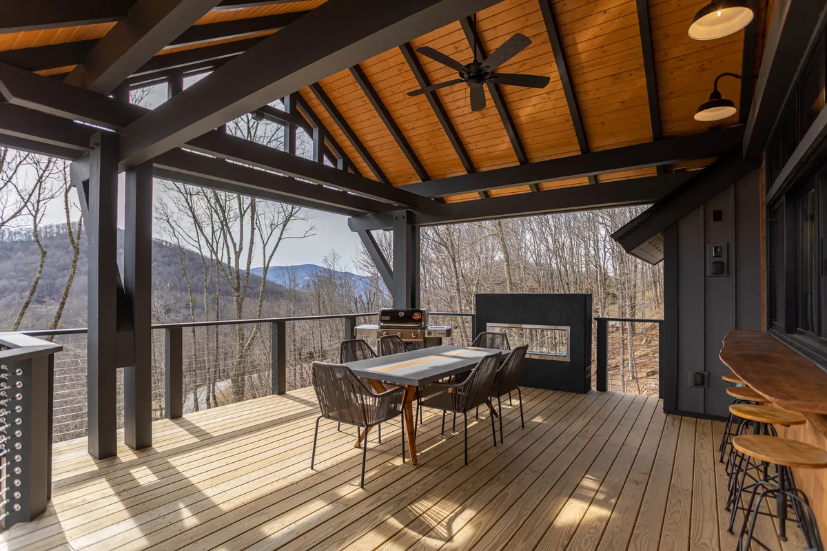 A spacious deck features a dining table and grill overlooking sweeping mountain vistas. The setting is perfect for barbecues, sunset dinners, and socializing with a view, emphasizing Bouldercrest’s expansive outdoor living areas.